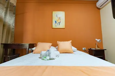 a bedroom with a bed with orange walls at Hotel El Cocobolo Food&Rest Room 5 B&B WiFi AC Pkg Free Swimmingpool in Liberia