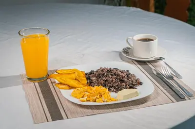 a plate of breakfast food and a glass of orange juice at Hotel El Cocobolo Food&Rest Room 6 B&B WiFi AC Pkg Free Swimmingpool in Liberia