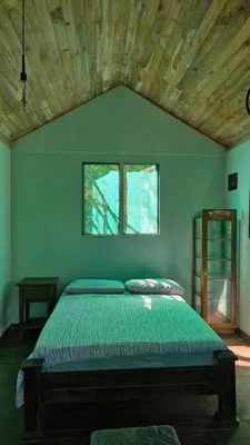a bedroom with a green bed with a wooden ceiling at PachaMama Bio Hostel in Tamarindo