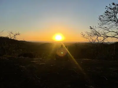 a person sitting on a hill watching the sunset at PachaMama Bio Hostel in Tamarindo