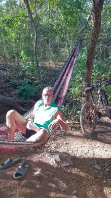 a man sitting in a hammock in the woods at PachaMama Bio Hostel in Tamarindo