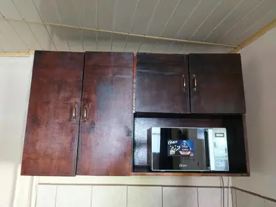a kitchen with wooden cabinets and a microwave at A 5 minutos del aeropuerto in Alajuela City