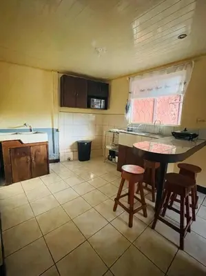 a kitchen with a table and two stools in it at A 5 minutos del aeropuerto in Alajuela City