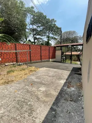an empty driveway in front of a red fence at A 5 minutos del aeropuerto in Alajuela City
