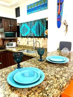 a kitchen with two blue plates and glasses on a counter at Jaco Hideaway Oasis in Jacó
