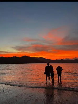 two people walking on the beach at sunset at Bioluminiscencia Hostel Tours - South in Paquera