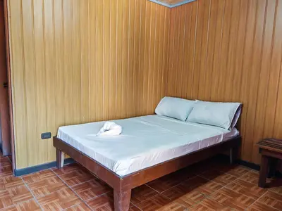 a bed in a room with a wooden wall at Bioluminiscencia Hostel Tours - South in Paquera