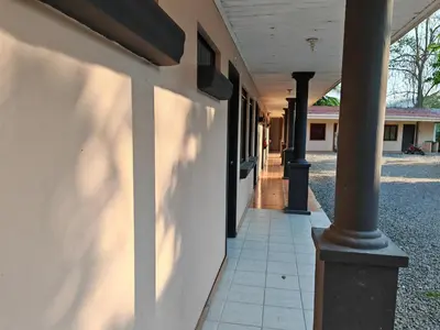 a building with a column next to a sidewalk at Bioluminiscencia Hostel Tours - South in Paquera