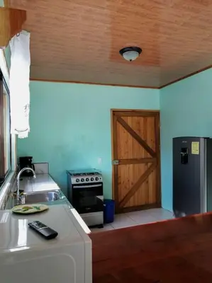 a kitchen with a sink and a refrigerator and a door at Casa Beli in Monteverde Costa Rica