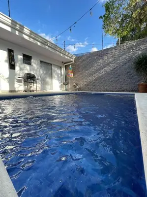 a pool of blue water in front of a house at Casa Encanto Luz del Mar, Con Piscina Privada in Herradura