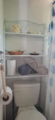 a bathroom with a toilet and a shelf with dishes at Casa Bus los Guanacastes in Veintisiete de Abril