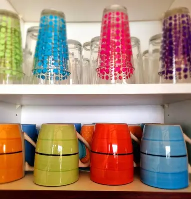 a row of colorful cups sitting on a shelf at Villa Amor del Mar with Breathtaking View of Ocean & Jungle in Dominical