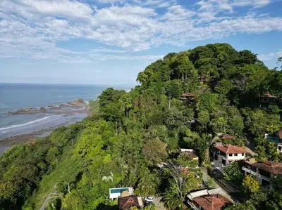 an island with houses on a hill next to the ocean at Villa Amor del Mar with Breathtaking View of Ocean & Jungle in Dominical