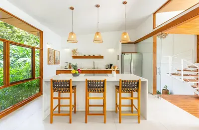 a kitchen with a white counter and wooden bar stools at Villa Laia - Santa Teresa in Santa Teresa Beach