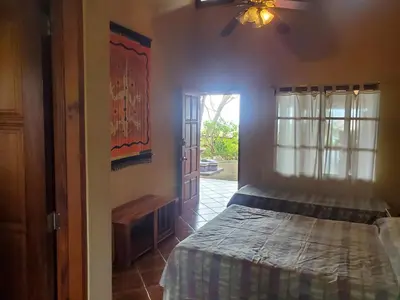 a bedroom with a bed and a door with a window at PACIFIC VISTA, Panoramic Beach & Ocean Views in Sámara