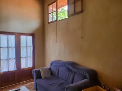 a living room with a blue couch and a window at PACIFIC VISTA, Panoramic Beach & Ocean Views in Sámara