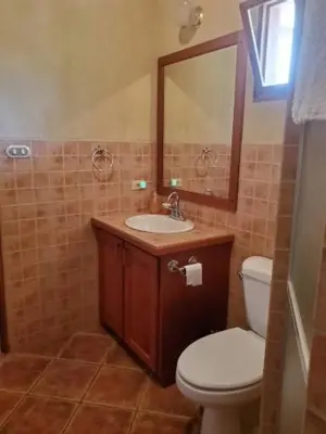 a bathroom with a toilet and a sink and a mirror at PACIFIC VISTA, Panoramic Beach & Ocean Views in Sámara
