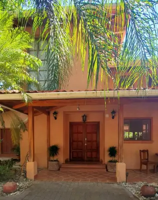 a house with a wooden door and palm trees at PACIFIC VISTA, Panoramic Beach & Ocean Views in Sámara