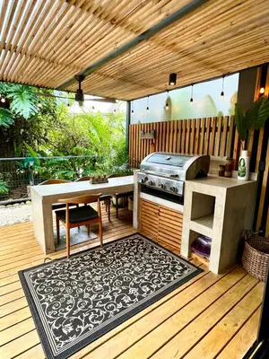 a patio with a grill and a table on a wooden deck at Studio Aloha - Malpais in Carmen