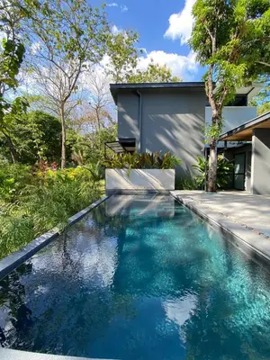 a swimming pool in front of a house with blue water at Studio Aloha - Malpais in Carmen