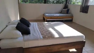 a bedroom with a bed and a chair and a window at Cabinas fave in Uvita