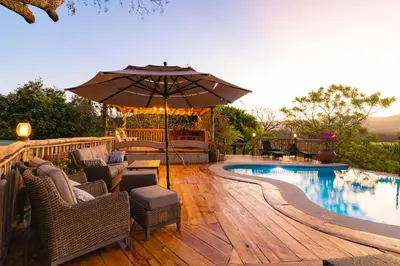 a patio with chairs and an umbrella next to a pool at Hacienda La Norma Boho Boutique Hotel in Veintisiete de Abril
