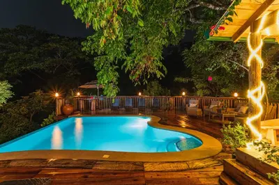 a swimming pool with lights in a backyard at night at Hacienda La Norma Boho Boutique Hotel in Veintisiete de Abril