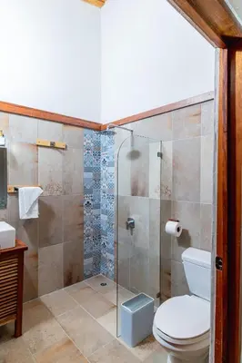 a bathroom with a toilet and a glass shower at Hacienda La Norma Boho Boutique Hotel in Veintisiete de Abril