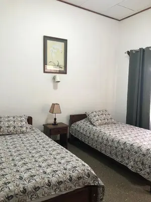 a bedroom with two beds and a table with a lamp at Hotel Del Aserradero in Liberia