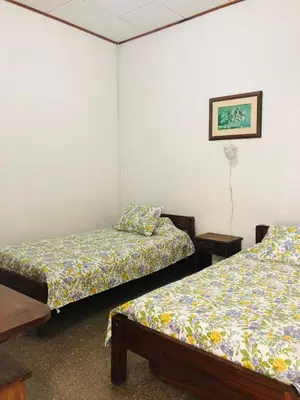 two beds in a room with white walls at Hotel Del Aserradero in Liberia