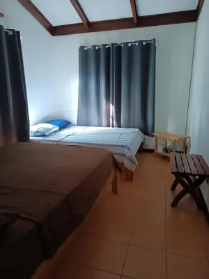 two beds in a room with blue curtains at House Manantial de Vida in Nandayure