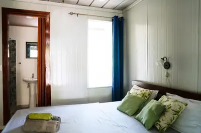 a bedroom with a bed with green pillows and a window at House in the palm forest in Carrillo