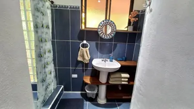 a blue tiled bathroom with a sink and a mirror at Cosy Apartment near the Lake in Tilarán