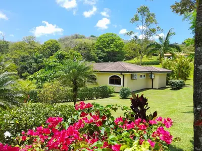 a house in a garden with pink flowers at Lakeview Arenal Suite - 2025-2026 Traveller Award Winners in Tronadora