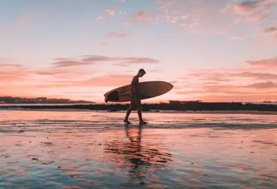 a man walking on the beach with a surfboard at Las Catalinas - Studio Cazenovia centrally located, short walk to beach in Playa Danta