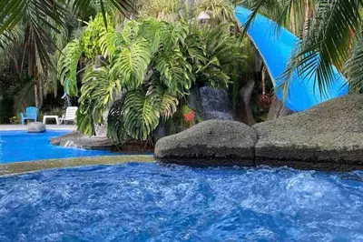 a large pool with blue water and palm trees at Villa Lapa in Agujas