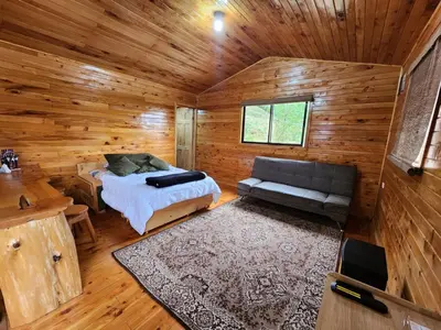 a room with a bed and a couch in a log cabin at Cabaña el Faisán, Jardín de Dota in Jardín