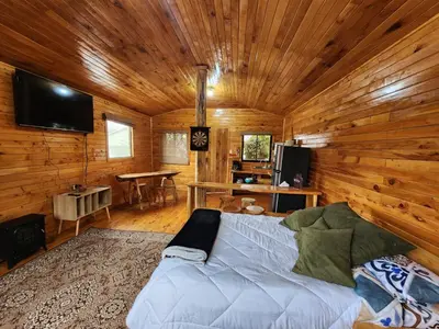 a living room with a bed in a log cabin at Cabaña el Faisán, Jardín de Dota in Jardín