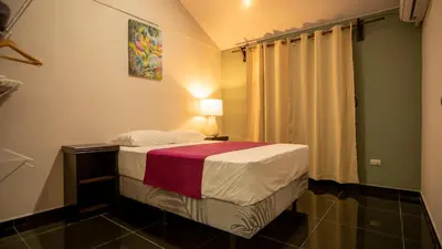 a small bedroom with a bed and a lamp at Anthurium house in Fortuna