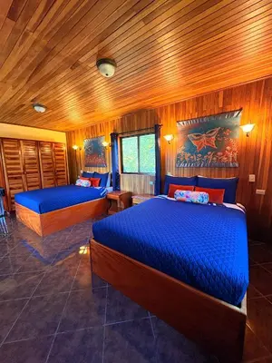 two beds in a room with wooden walls at TucanTico Lodge ~ Casa # 3 in Monteverde Costa Rica