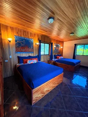 two beds in a room with wooden walls at TucanTico Lodge ~ Casa # 3 in Monteverde Costa Rica