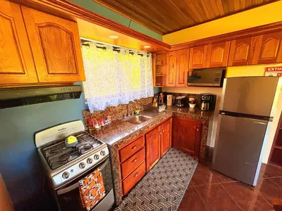 a kitchen with wooden cabinets and a stove and a refrigerator at TucanTico Lodge ~ Casa # 3 in Monteverde Costa Rica