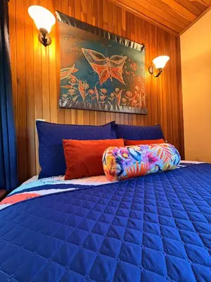 a bedroom with a bed with a blue comforter at TucanTico Lodge ~ Casa # 3 in Monteverde Costa Rica