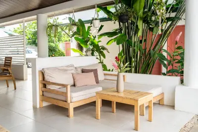 a patio with a couch and a table and plants at Hotel Por Que No? in Uvita