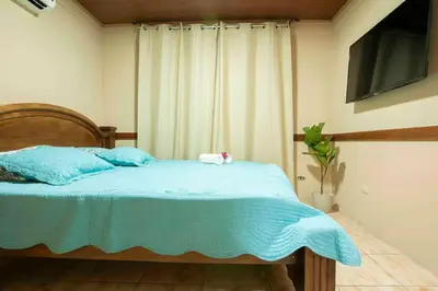 a bedroom with a bed with blue sheets and a television at Villa Buganvilia Fortuna Centro in Fortuna