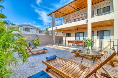 a patio of a house with benches and a table at Muna Tamarindo in Tamarindo