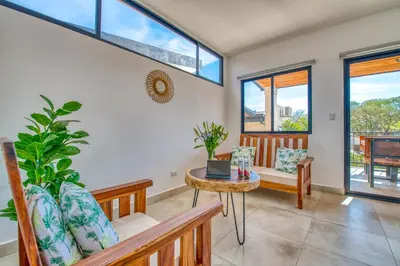 a living room with a table and chairs and windows at Muna Tamarindo in Tamarindo