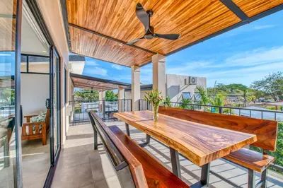 a wooden table on a balcony with benches at Muna Tamarindo in Tamarindo