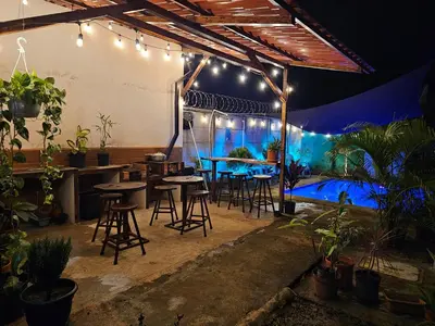 a patio with tables and chairs and a pool at night at Casa Luna, espacio moderno y acogedor in Liberia