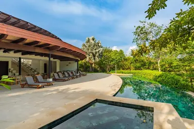 an outdoor swimming pool with chairs and a house at Modern 3BR Condo with Partial Ocean View - Carao - Reserva Conchal Golf Resort in Playa Conchal